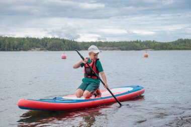 Baltık Denizi 'nde sörf tahtasında, Finlandiya Körfezi' nde, çocuk tatili, Finlandiya 'da aktif yaz tatili.