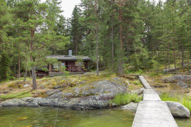 Finlandiya 'da Baltık Denizi yakınlarında kuzey çam ormanları olan adanın takımadalarında Finlandiya' daki sauna evi ve dubası.