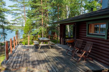 Finlandiya 'da Baltık Denizi yakınlarında Finlandiya' da çam ormanı olan ve takımadalarda sandalyeleri olan sauna evi, saunadan sonra dinlenme yeri..