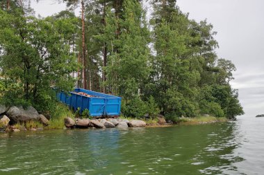 Sauna sobasında yanmak için yakılacak odun. Mavi bir konteynırda ince ince doğranmış ve istiflenmiş. Yığınla kuru odun Finlandiya 'da bir adaya getirildi, odun teslimatı..