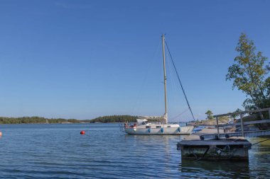 Finlandiya, Baltık Denizi 'ndeki adanın limanında bir şamandıraya bağlı yelkenli, Baltık Denizi' ndeki sahil limanında yat ve güneşli havada yelkenli tekneler için güvenli bir liman.