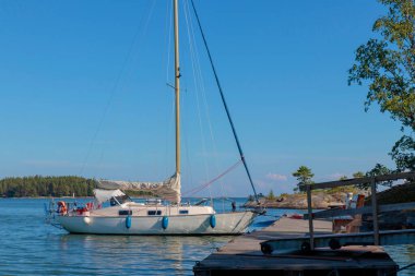 Finlandiya, Baltık Denizi 'ndeki adanın limanında bir şamandıraya bağlı yelkenli, Baltık Denizi' ndeki sahil limanında yat ve güneşli havada yelkenli tekneler için güvenli bir liman.