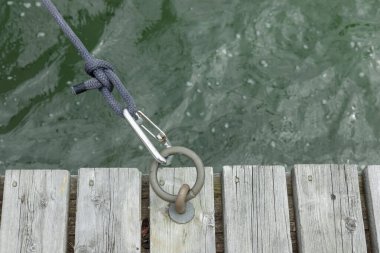 Tahta rıhtımdaki botlar için demirli paslanmaz çelik halkalar karabina ve yelkenli teknesinden siyah ip, halat düğümü, Finlandiya