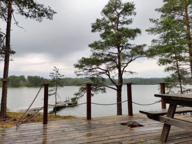 Terrace of Finnish summer sauna house with chairs in the archipelago, island with pine forest in Finland near the Baltic sea, rest after sauna. clipart