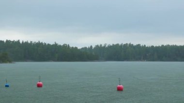 Finlandiya 'da Baltık Denizi' nin sakin sularında yağmur altında yüzen kırmızı şamandıralar, takımadalarda marina, Finlandiya Körfezi 'ndeki adalar