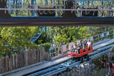 Helsinki, Finlandiya - 19 AĞUSTOS 2024: Hız treni Tulireki ile Linnanmaki lunaparkı, arka planda mavi gökyüzü, mutlu insanlar