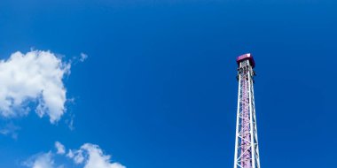 Helsinki, Finlandiya - 19 AĞUSTOS 2024: Linnanmaki lunaparkı, hareket halindeki Raketti biniş kulesi, arka planda mavi gökyüzü, mutlu insanlar