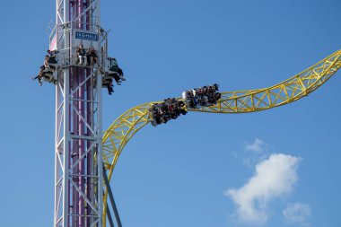 Helsinki, Finlandiya - 19 AUGust 2024: Linnanmaki lunaparkı hız treni Ukko ile hareket halindeki Raketti kulesine biniyor, arka planda mavi gökyüzü, mutlu insanlar