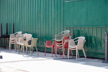 Güneşli bir günde beyaz ve kırmızı plastik sandalyeler kafe terasının yanındadır. Kalıplı yığın plastik sandalyeler, metin için boşluk