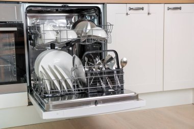 Zaman kazandıran teknoloji. Dahili bulaşık makinesini aç. Entegre aletleri olan beyaz mutfak. Bulaşık makinesinde temiz tabaklar ve bulaşıklar