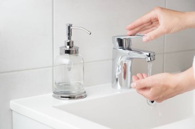 İç tuvalette el yıkama prosedürü için ilaç şişesinden sıvı sabun kullanan bir kadın görüntüsü. Kadın dezenfektan jeli ya da antibakteriyel temizleyici kullanıyor. Hijyen kavramı