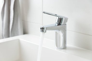 Modern banyo musluğu, akan su ve beyaz lavabolu su musluğu, saf su konsepti, doğal başvurular kavramının fotokopi alanı ile korunması.
