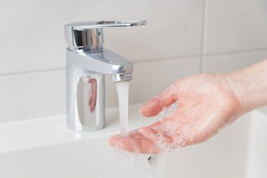 Lavaboda akan su, cilt bakımı konsepti, beyaz minimalist banyo.