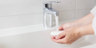 Lavaboda akan su, cilt bakımı konsepti, beyaz minimalist banyo.