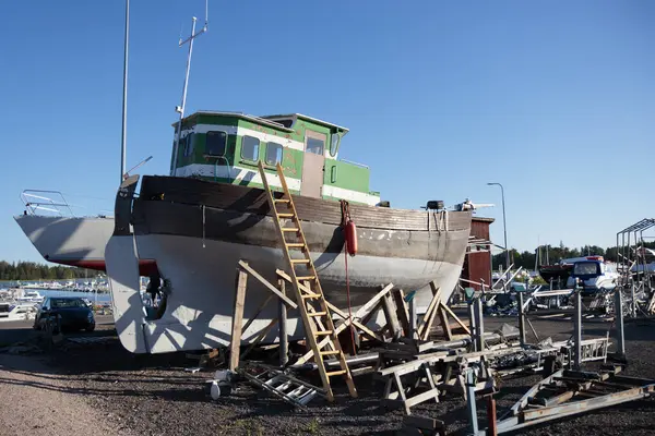 Metal yat, karaya inmeden önce kış depolama ve onarım işleri için liman iskelesinde eski bir tekne.