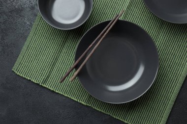 Boş Japon yemekleri. Çin noodle veya Tay çorba için siyah seramik kase bamkuk halıya yatıyor. Soya sosu ve kırmızı Çin için beyaz saucepot bir siyah arka plan üzerine yapışır. Üstten görünüm, kopya alanı