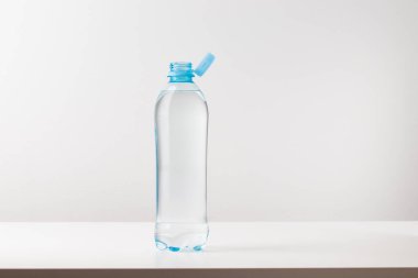 Beyaz arka planda durağan plastik kapaklı bir şişe. Yeni tasarım, kapağın açıldıktan sonra şişeye bağlı kalması ve tüm paketin toplanıp geri dönüşümünün kolaylaştırılması anlamına geliyor. Yüksek kaliteli fotoğraf.