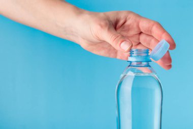 PET şişesinde insan eliyle durgun plastik kapak. Yeni tasarım, kapağın açıldıktan sonra şişeye bağlı kalması ve tüm paketin toplanıp geri dönüşümünün kolaylaştırılması anlamına geliyor. Yüksek kalite fotoğraf