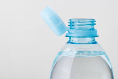 Gri arka planda izole edilmiş plastik bir şişeye yeni bir kapak iliştirilmiş. Çevre koruma kavramı