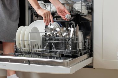 Bir kadın bulaşık makinesine alüminyum folyo koyuyor, maliyetli, çevre dostu, ve son derece etkili hack, gümüş çatal bıçak, cam ve çatal bıçak, kimyasal reaksiyonlar, aşınma önleme