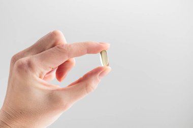 Omega 3 balık yağı kapsüllerini pembe arka planda tutan parmaklar. Vitaminleri tutan kadın el, yakın plan. Sağlık, takviye, D vitamini, hastalıkların tedavisi kavramı. Yüksek kalite fotoğraf