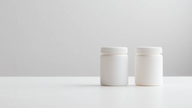 Fotokopi alanı olan beyaz bir arka planda beyaz plastik ilaç şişeleri. İlaç ve sağlık konseptleri içinde haplar veya vitaminler olan bir kavanoz içerir. Yüksek kaliteli fotoğraf afişi