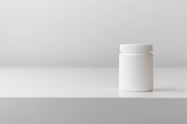 Fotokopi alanı beyaz arka planda beyaz plastik ilaç şişesi. İlaç ve sağlık konseptleri içinde haplar veya vitaminler olan bir kavanoz içerir. Yüksek kaliteli fotoğraf maketi afişi