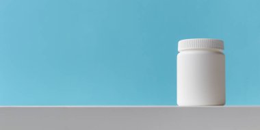 Mavi arka planda fotokopi alanı olan beyaz plastik ilaç şişesi. İlaç ve sağlık konseptleri içinde haplar veya vitaminler olan bir kavanoz içerir. Yüksek kalite fotoğraf modeli afişi. Sağlıklı Biyolojik Ek