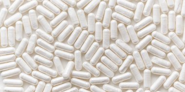 Dağılmış beyaz ilaç, haplar veya kapsüller beyaz masada. Üst görünümden arkaplanı düzenle. Tıbbi, eczane ve sağlık hizmetleri. Yüksek kalite fotoğraf modeli afişi. Sağlıklı Biyolojik İlaveler. Farmakoloji