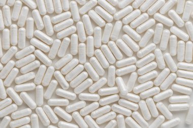 Dağılmış beyaz ilaç, haplar veya kapsüller beyaz masada. Üst görünümden arkaplanı düzenle. Tıbbi, eczane ve sağlık hizmetleri. Yüksek kalite fotoğraf modeli afişi. Sağlıklı Biyolojik Ek.