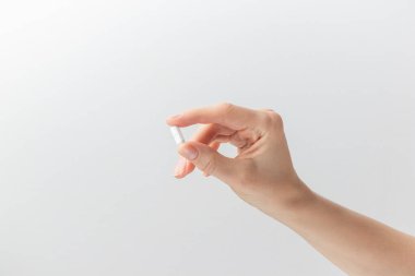 Beyaz arka planda parmakları olan beyaz hapları tutan bir kadın. Sağlık hizmeti kavramı, beslenme takviyeleri, depresyon ve hastalıkların tedavisi. Yüksek kaliteli fotoğraf afişi