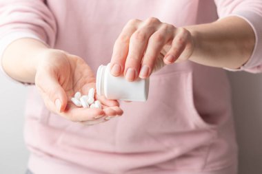 Bir kadının eli avucunun içine beyaz haplar döker. Sağlık konsepti, besin takviyeleri, depresyon ve hastalıkların tedavisi