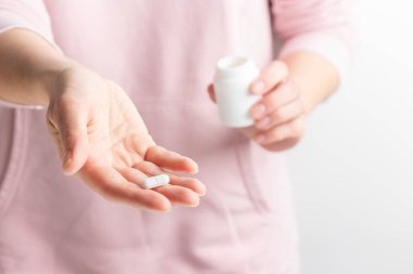 Beyaz arka planda parmakları olan beyaz hapları tutan bir kadın. Sağlık hizmeti kavramı, beslenme takviyeleri, depresyon ve hastalıkların tedavisi. Yüksek kaliteli fotoğraf maketi afişi