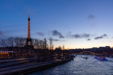 Paris, Fransa - 24 Şubat 2025: Aydınlatılmış Eyfel Kulesi ve Paris, Fransa 'daki Seine nehri üzerindeki Pont Debilly Footbridge' in gece manzarası