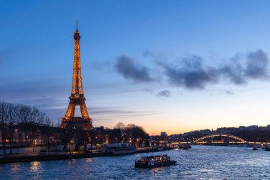 Paris, Fransa - 24 Şubat 2025: Aydınlatılmış Eyfel Kulesi ve Paris, Fransa 'daki Seine nehri üzerindeki Pont Debilly Footbridge' in gece manzarası