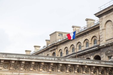 Paris, Fransa, 22 Şubat 202: Bir Fransız bayrağı, Paris 'in ulusal gururunu, şehrin zarif mimarisini ve zamansız cazibesini simgeleyen klasik bir Paris binasında gururla dalgalanıyor
