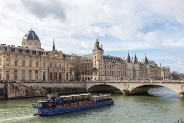 Paris, Fransa - 23 Şubat 2025: Seine nehri üzerindeki Conciergerie Kalesi ve Değişim Köprüsü 'nün güzel turistik teknesi. Castle, Cite Adası 'nın batısında bulunan eski bir hapishane.