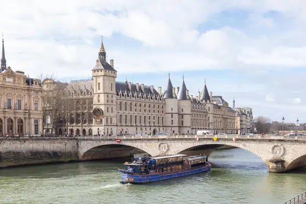 Paris, Fransa - 23 Şubat 2025: Seine nehri üzerindeki Conciergerie Kalesi ve Değişim Köprüsü 'nün güzel turistik teknesi. Castle, Cite Adası 'nın batısında bulunan eski bir hapishane.