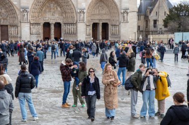 Paris, Fransa - 22 Şubat 2025: Notre-Dame de Paris ve yeniden inşa edildikten sonra yeni açılan bir katedralin önünde turistler
