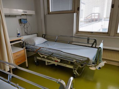 Espoo, Finlandiya - 14 Nisan 2025: Jorvin Hastanesi 'ndeki hastane yatağı (Jorvinsairaala), arka planda beyaz duvarlar, minimum mobilyalar ve tıbbi gereçler bulunan modern bir Finlandiya sağlık merkezi..