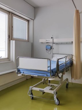 Espoo, Finlandiya - 14 Nisan 2025: Jorvin Hastanesi 'ndeki hastane yatağı (Jorvinsairaala), arka planda beyaz duvarlar, minimum mobilyalar ve tıbbi gereçler bulunan modern bir Finlandiya sağlık merkezi..