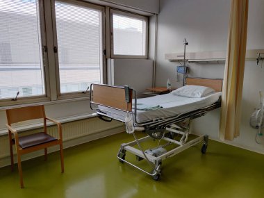 Espoo, Finlandiya - 14 Nisan 2025: Jorvin Hastanesi 'ndeki hastane yatağı (Jorvinsairaala), arka planda beyaz duvarlar, minimum mobilyalar ve tıbbi gereçler bulunan modern bir Finlandiya sağlık merkezi..