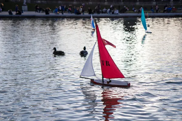 Paris, Fransa - 22 Şubat 2025: Lüksemburg Bahçesi 'ndeki (Jardin du Lüksemburg) merkez çeşmesinin etrafında toplanan çocuklar ve aileler, renkli yelkenli tekneleri denize indiriyorlar.