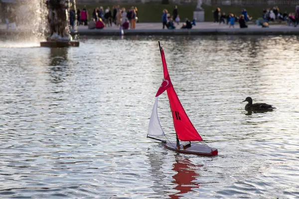 Paris, Fransa - 22 Şubat 2025: Lüksemburg Bahçesi 'ndeki (Jardin du Lüksemburg) merkez çeşmesinin etrafında toplanan çocuklar ve aileler, renkli yelkenli tekneleri denize indiriyorlar.