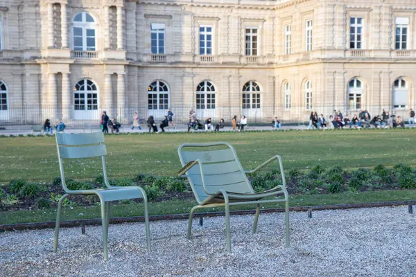 Paris, Fransa - 22 Şubat 2025: Paris 'teki Lüksemburg Bahçesi' nin (Jardin du Lüksemburg) manzarası. Klasik Paris halk parkı sandalyeleri, ziyaretçiler merkez çeşmenin yanında dinleniyor.