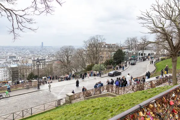 Paris, Fransa - 28 Şubat 2025: Paris 'in Kutsal Yüreği Bazilikası' ndaki (Sacre-Coeur) terastan manzara, balkondaki turistler şehir manzarasına hayran. Korkuluklar aşk kilitleriyle süslenmiş.