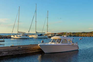 Jurmo, Pargas, Finlandiya - 1 Temmuz 2025: Jurmo adasında yaz mevsiminde demirlemiş yelkenli ve motorlu tekne marinası, rıhtıma yanaşmış ve günbatımında şamandıralara bağlanmış.