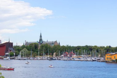 Stockholm, İsveç - 9 Temmuz 2025: Djurgarden Adası 'ndaki Vasahamnen marinası, güneşli bir yaz gününde Vasa Müzesi ve Viking Müzesi yakınlarına yanaşan turistik yelkenli ve yatlarla