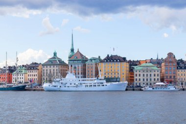 İsveç 'in Stockholm kentindeki Eski Kent (Gamla Stan) manzarası, renkli tarihi binalar, dar sokaklar, geleneksel İskandinav mimarisi ve limana demirlemiş tekneler.