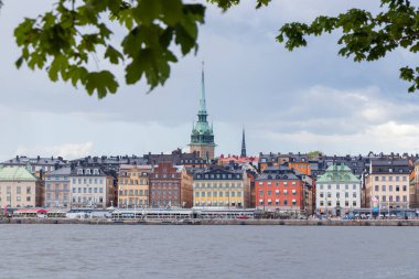 Stockholm, İsveç 'teki Eski Şehir Gamla Stan manzarası. Renkli tarihi binalar, dar sokaklar, geleneksel İskandinav mimarisi ve limana demirlemiş tekneler.